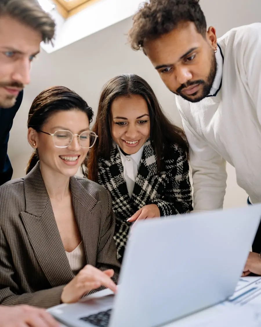 Equipe animada reunida em volta de um notebook