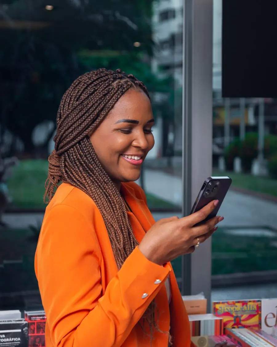 Mulher sorrindo com o celular na mão